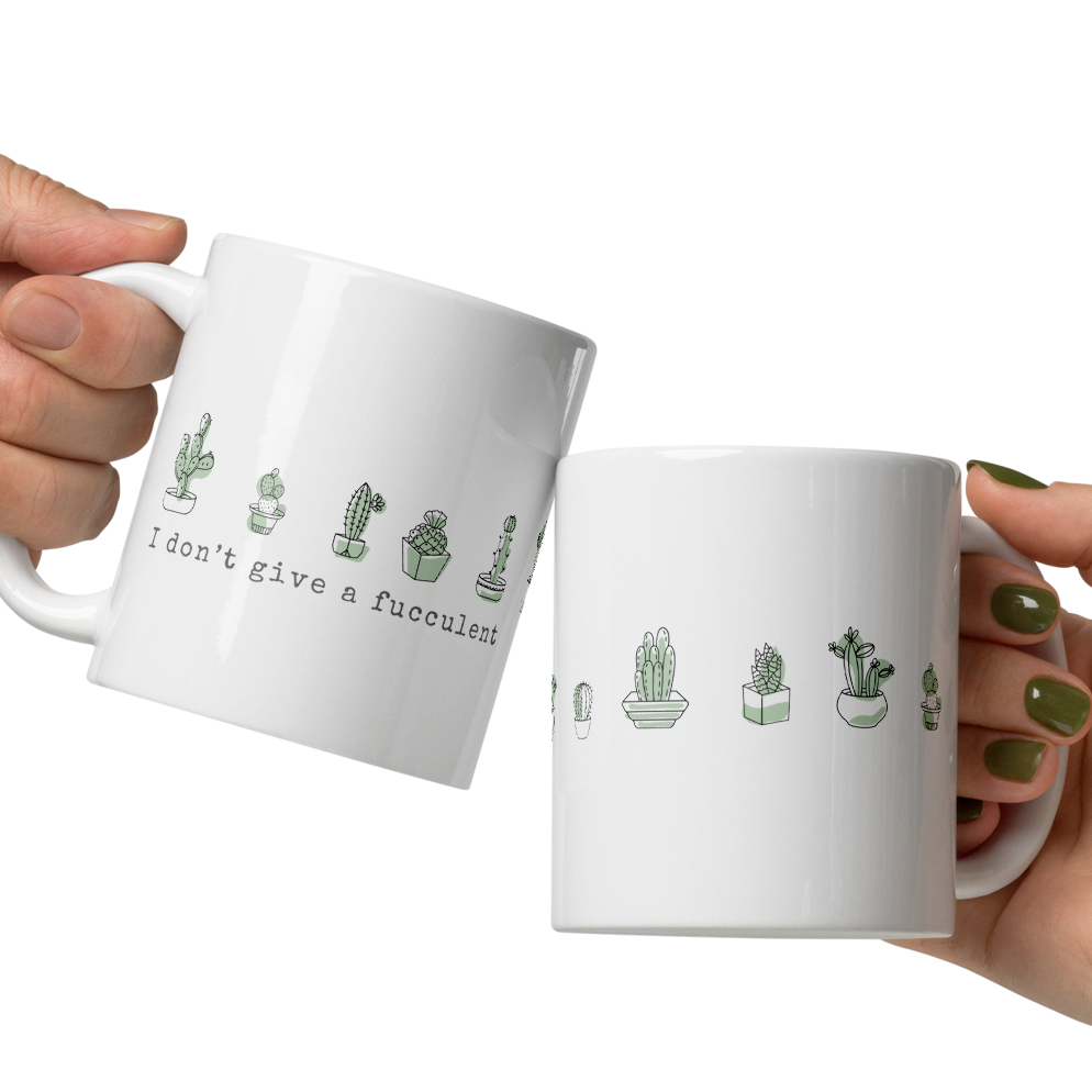 Two white mugs with cactus illustrations and text held by two hands on a white background