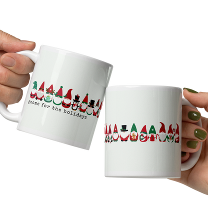 Two hands holding white mugs with Christmas-themed designs on a white background