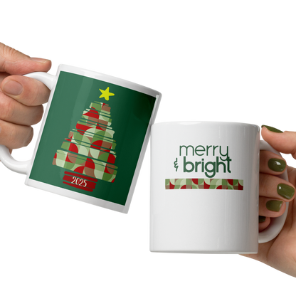 Two hands holding Christmas-themed mugs with tree and 'merry & bright' designs.
