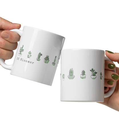 Two white mugs with cactus illustrations held by hands on a white background