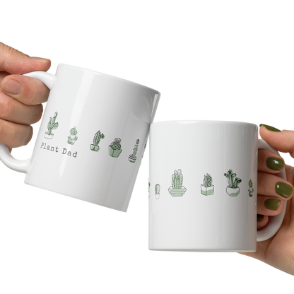 Two white mugs with cactus illustrations and text held by a hand on a white background