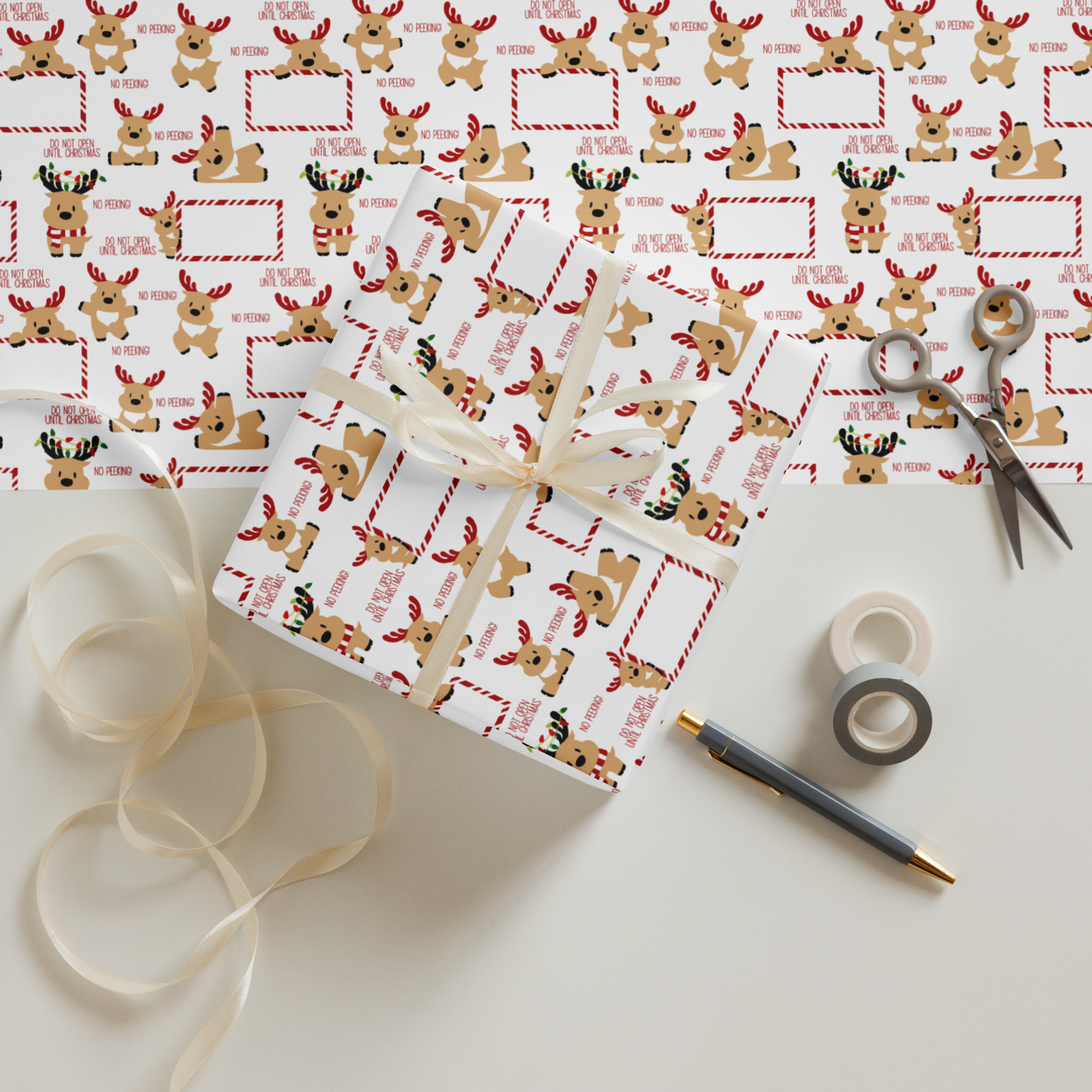 Gift wrap with reindeer design, ribbon, scissors, and tape on a white surface