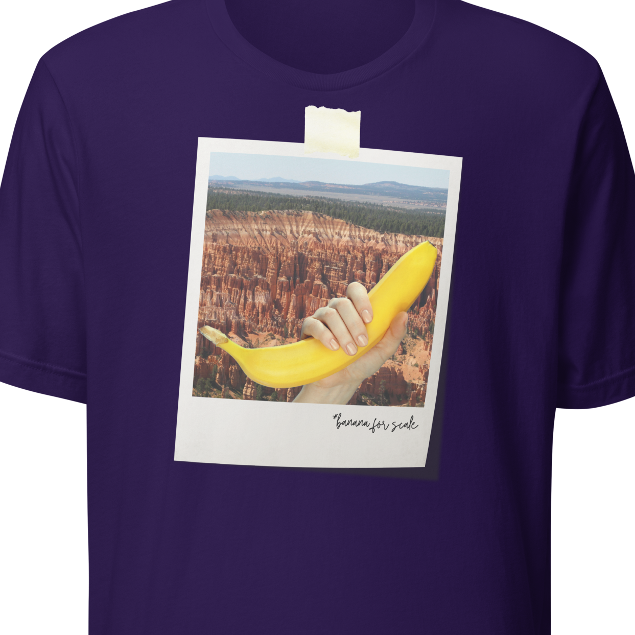 Purple t-shirt with a graphic of a hand holding a banana over a scenic landscape, on a white background.