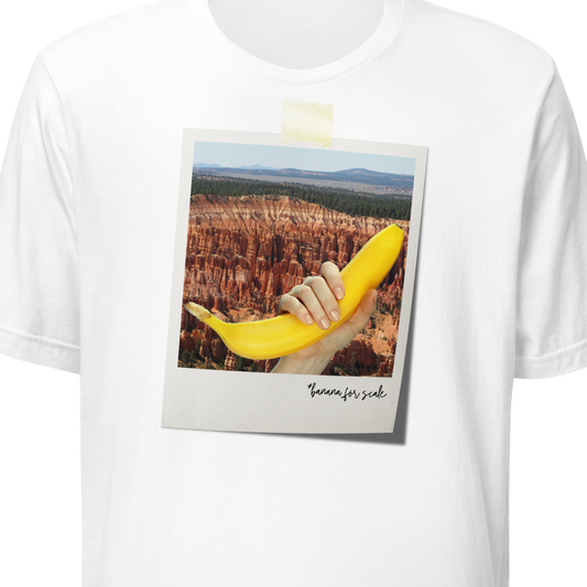 White t-shirt with a graphic of a hand holding a banana over a desert landscape, on a white background.