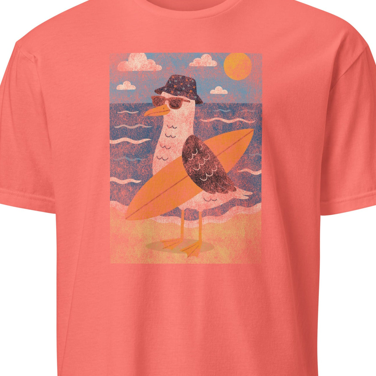 Coral t-shirt with a graphic of a seagull on a surfboard against a beach background.