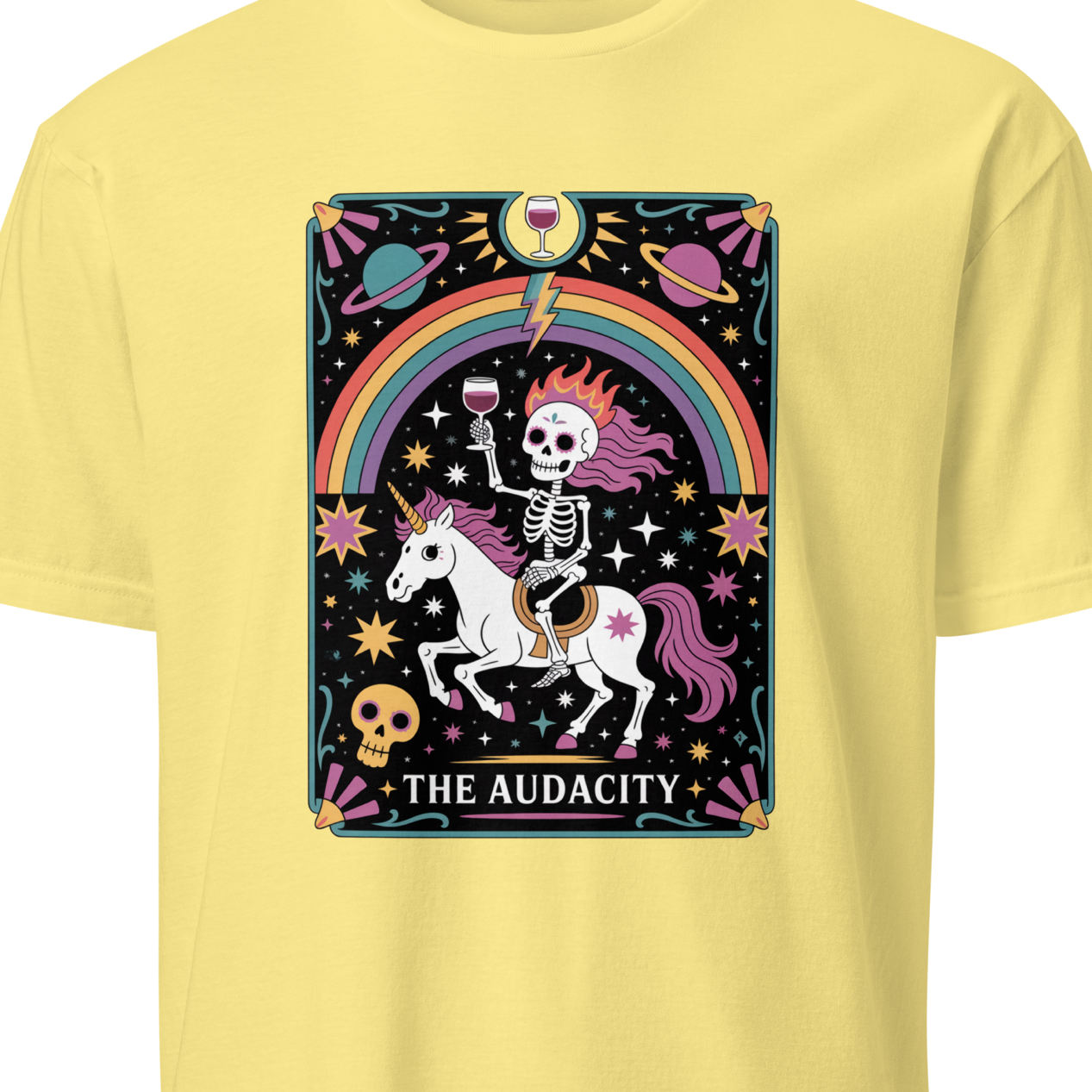 Yellow t-shirt with a colorful graphic of a skeleton on a unicorn, rainbow, and text 'The Audacity'