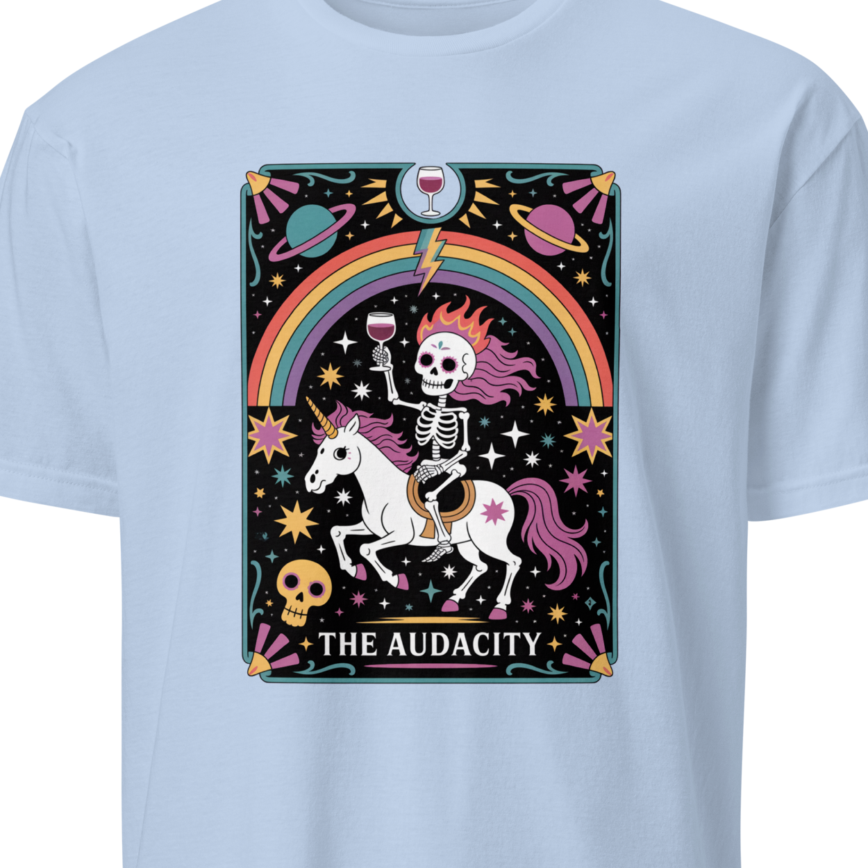 Light blue t-shirt with a colorful graphic of a skeleton on a unicorn, rainbow, and text 'The Audacity' 