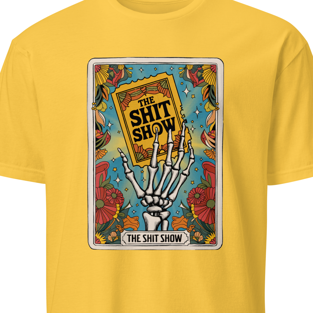 Yellow t-shirt with a graphic design featuring a skeleton hand holding a book titled 'The Shit Show' 