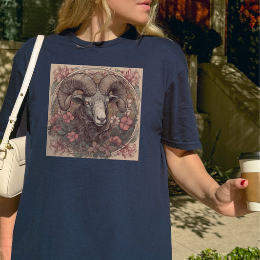 Person wearing a navy blue t-shirt with a graphic design of a ram and flowers, holding a coffee cup outdoors.