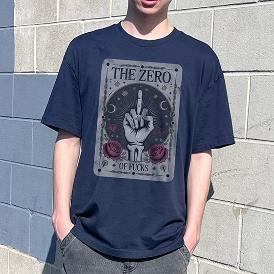 A person wearing an oversized navy blue graphic t-shirt with a vintage-style hand gesture print and gray cargo pants, standing against a gray concrete block wall.