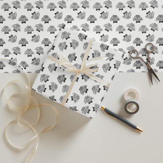 Gift wrapped in black and white patterned paper with ribbon, scissors, and tape on a matching background.