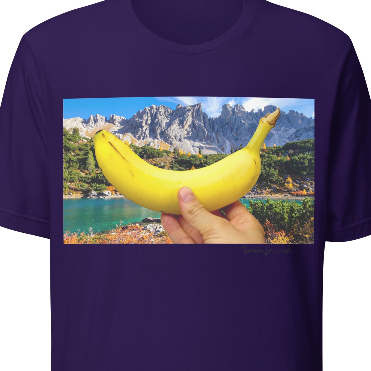Purple t-shirt with a graphic of a hand holding a banana over a scenic landscape on a white background