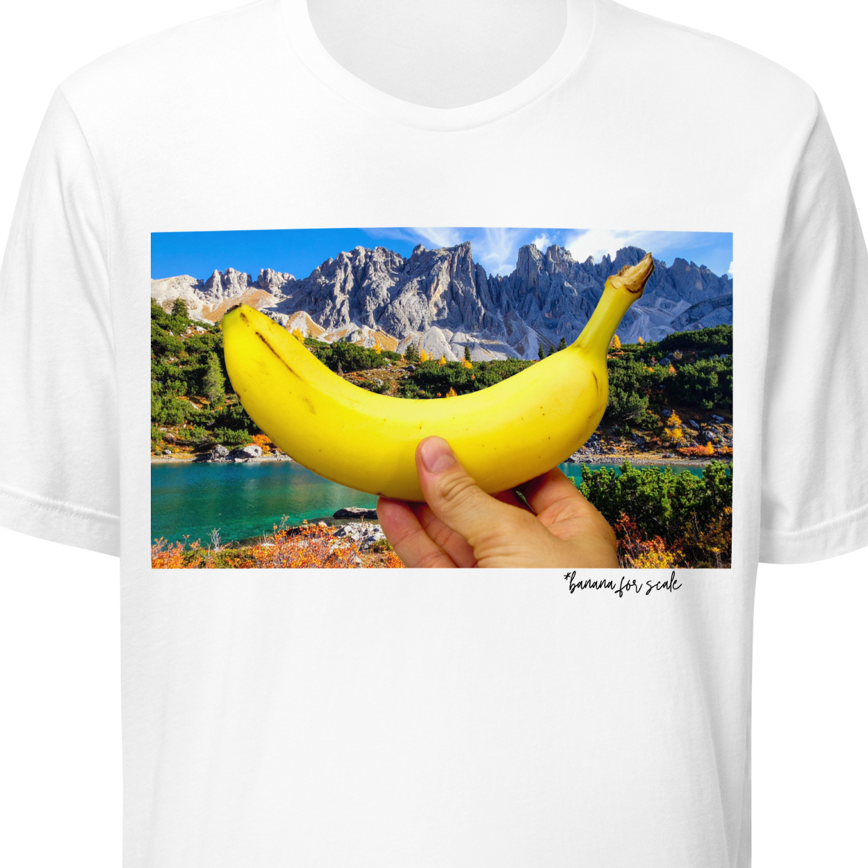 White t-shirt with a graphic of a hand holding a banana over a scenic landscape.