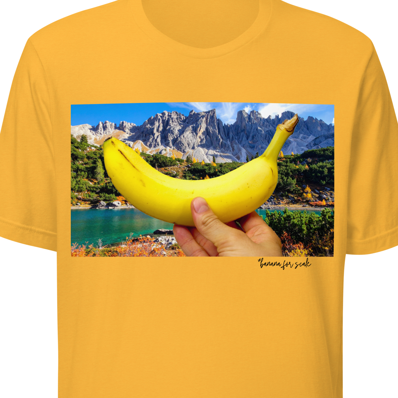 Yellow t-shirt with a scenic print of a hand holding a banana over a landscape.