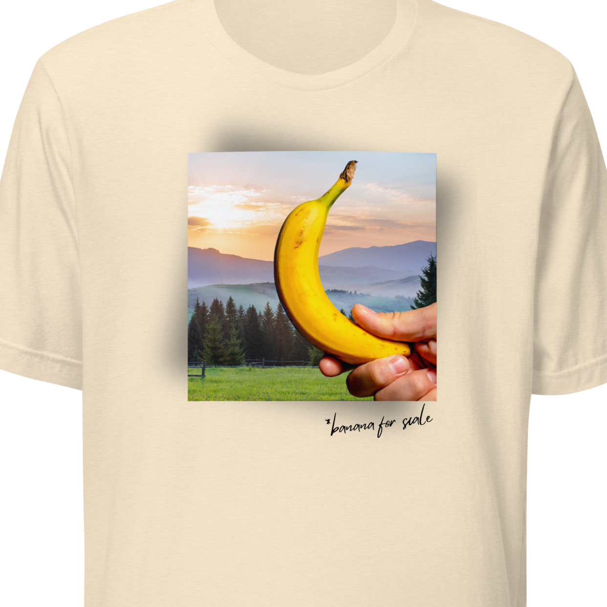 Beige t-shirt with a graphic of a hand holding a banana and a sunset landscape on a white background