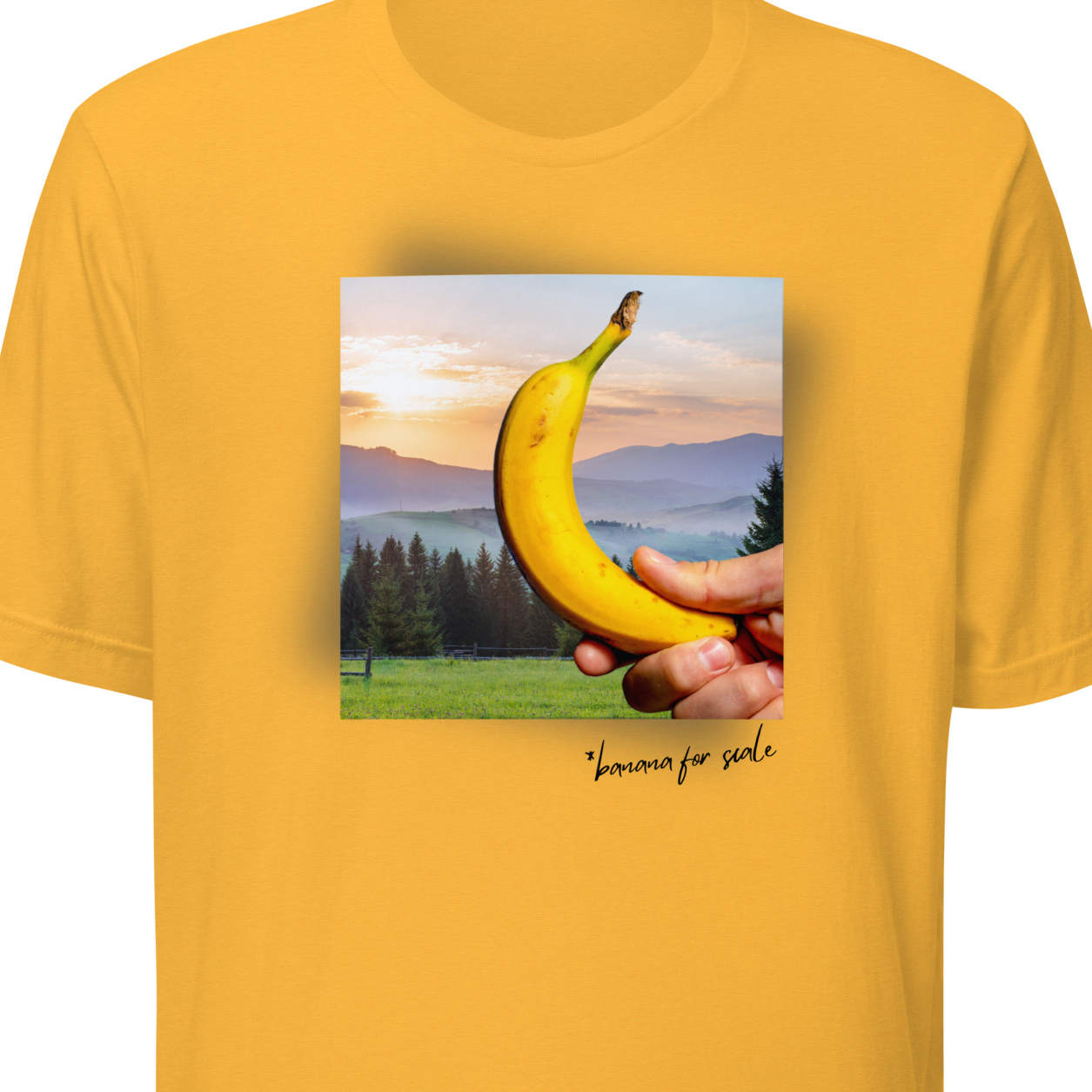 Yellow t-shirt with a graphic of a hand holding a banana against a scenic background on a white background